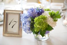 a vase filled with blue and white flowers next to a framed number seven sign on a table