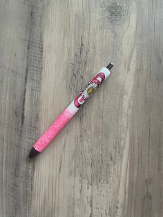 a pink pen sitting on top of a wooden table