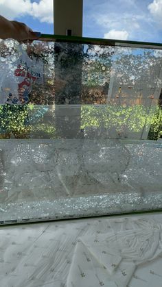 a person is holding something in front of a window that has shattered glass on it