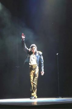 a man standing on top of a stage with his hands in the air