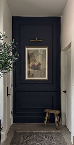 an entryway with a bench and framed painting on the wall, along with a potted plant