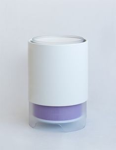 a white and purple vase sitting on top of a white table next to a wall