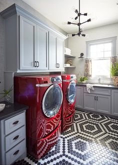 a red washer and dryer sitting in a kitchen next to each other on a tiled floor