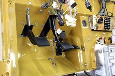 the inside of a yellow vehicle with some wires and other items hanging from it's side