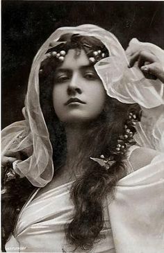 an old black and white photo of a woman with long hair wearing a veil over her head