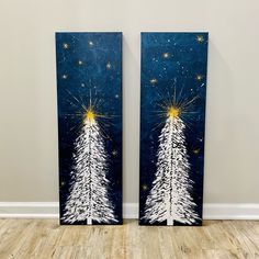 two canvases with christmas trees painted on them in front of a white and blue wall