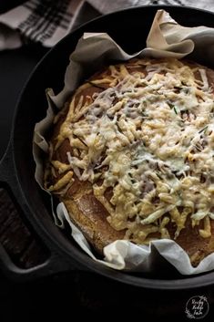 a pan filled with food sitting on top of a table next to a napkin and fork