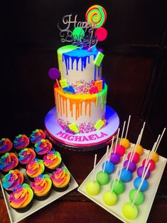 a birthday cake and cupcakes are on the table next to some candies