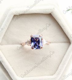 an engagement ring with blue and white sapphires in a velvet box on top of a table