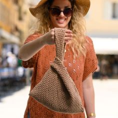 a woman wearing a hat and holding a knitted bag