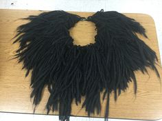 a large black feathered necklace on top of a wooden table