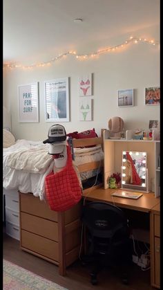 a bedroom with a bed, desk and mirror in it's corner is lit up by fairy lights