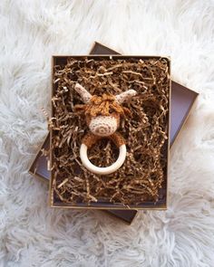 a stuffed cow is in a box with some wood shavings