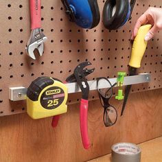 there are many tools hanging on the pegs in this workbench, and one person is using a pair of pliers