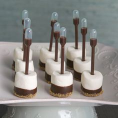 chocolate and marshmallow desserts are arranged on a white platter with candles