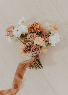 a bouquet of flowers is tied to a piece of paper on the floor with a brown ribbon