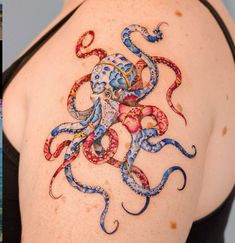 an octopus tattoo is on the back of a woman's shoulder and it appears to be in color