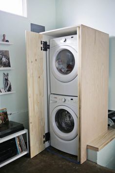 a washer and dryer in a room with wooden shelves on the wall next to each other