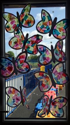 some colorful paper butterflies hanging from a window