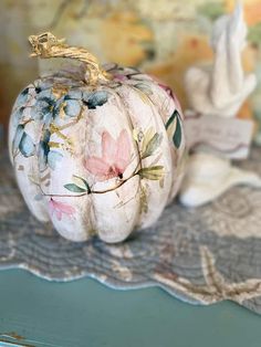 a painted pumpkin sitting on top of a table next to a wallpapered background