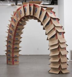 an arch made out of cardboard boxes in the middle of a room with white walls