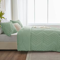 a bed in a bedroom with green comforter and pillows