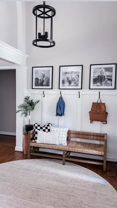 a bench in the corner of a room with pictures on the wall and a rug