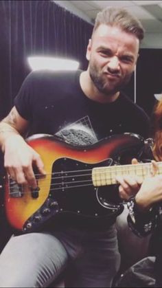 a man and woman sitting next to each other while playing guitar instruments in front of them