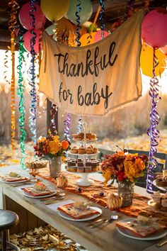 a table set up for a baby's first birthday with balloons and streamers