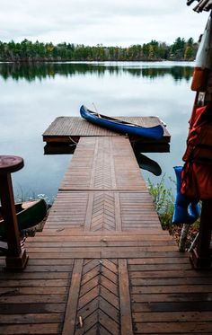 there is a boat docked at the end of a dock with two kayaks on it