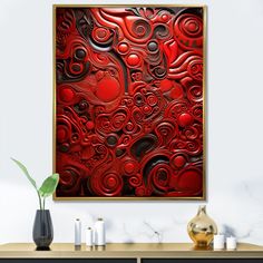 a red abstract painting hanging on a wall above a table with candles and vases