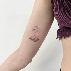 a woman with a book tattoo on her arm