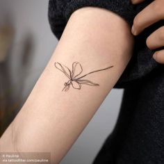 a woman's arm with a small flower tattoo on it