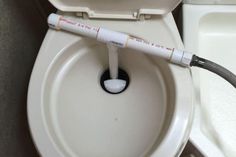 an electronic device is connected to the back of a toilet bowl with its lid open