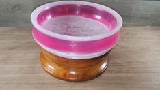 a pink and white bowl sitting on top of a wooden table