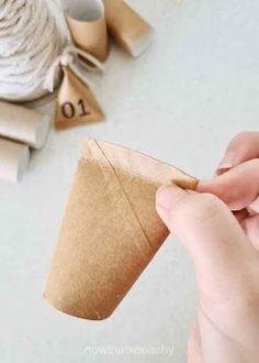 someone is holding a piece of brown paper in front of some twine spools