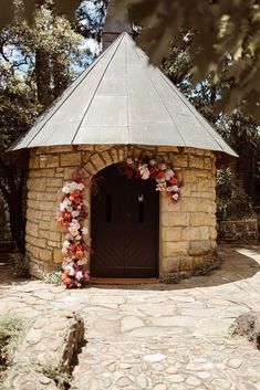 a stone building with flowers on the front door and side entrance to an outdoor area