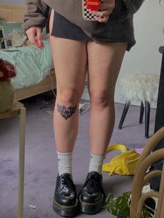 a person with tattoos on their legs standing in a room