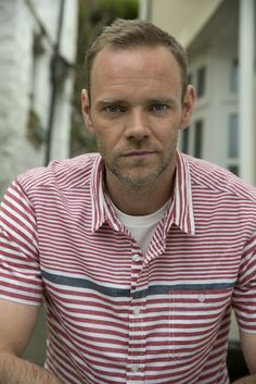 a man in a red and white striped shirt is sitting down with his hands on his hips