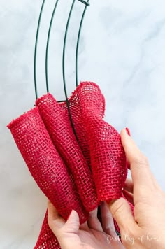 a person is holding some red cloth on a wire hanger with two pins in it