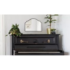 a black piano sitting next to a mirror and potted plant on top of it