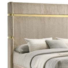 an upholstered headboard with gold trimmings and pillows on a bed