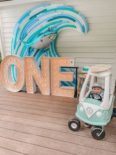 a child's ride on toy car in front of a sign that says one