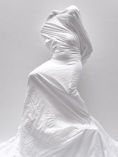 a woman in a white dress is standing with her back turned to the camera and she's covered up