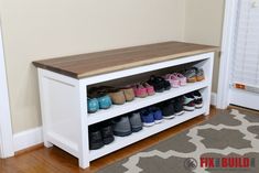 a white bench with shoes on it in front of a wall and carpeted floor