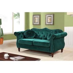 a green couch in a living room next to a coffee table and potted plant