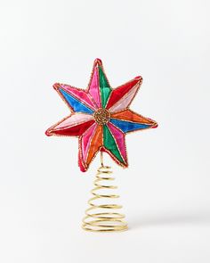 a multicolored christmas star decoration on top of a spiral wire tree ornament