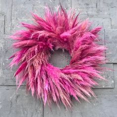 a pink wreath is hanging on the wall next to a gray brick wall and concrete floor