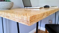 a wooden table with black metal legs and a laptop on the desk in front of it