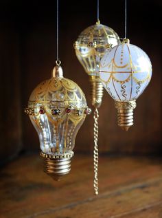 three decorative light bulbs hanging from strings on a wooden floor in front of a wall